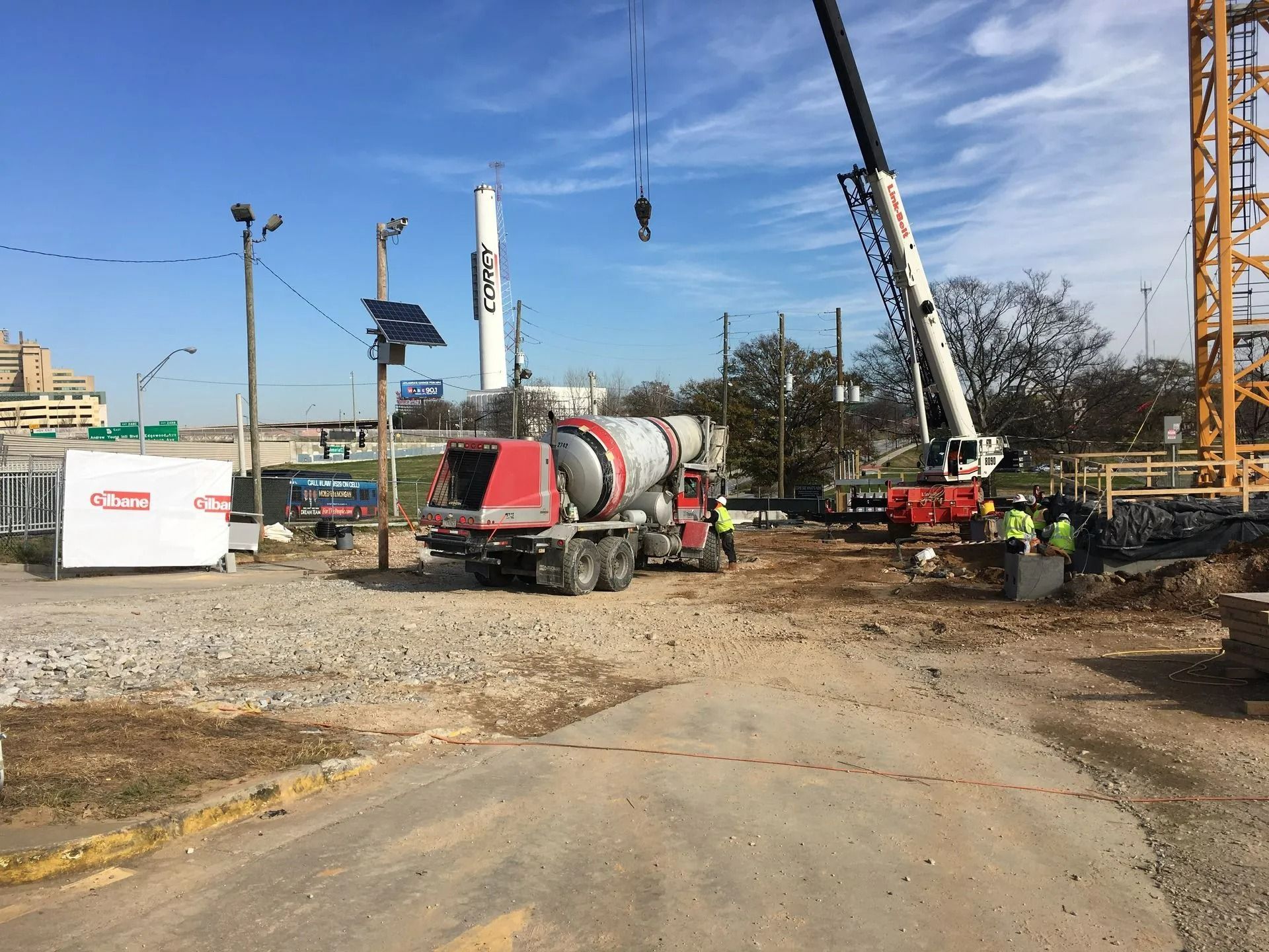 Construction site with cement truck, crane, and workers pouring concrete.