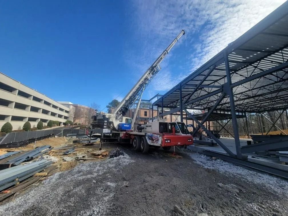 Crane lifting steel beams at a construction site on a sunny day.
