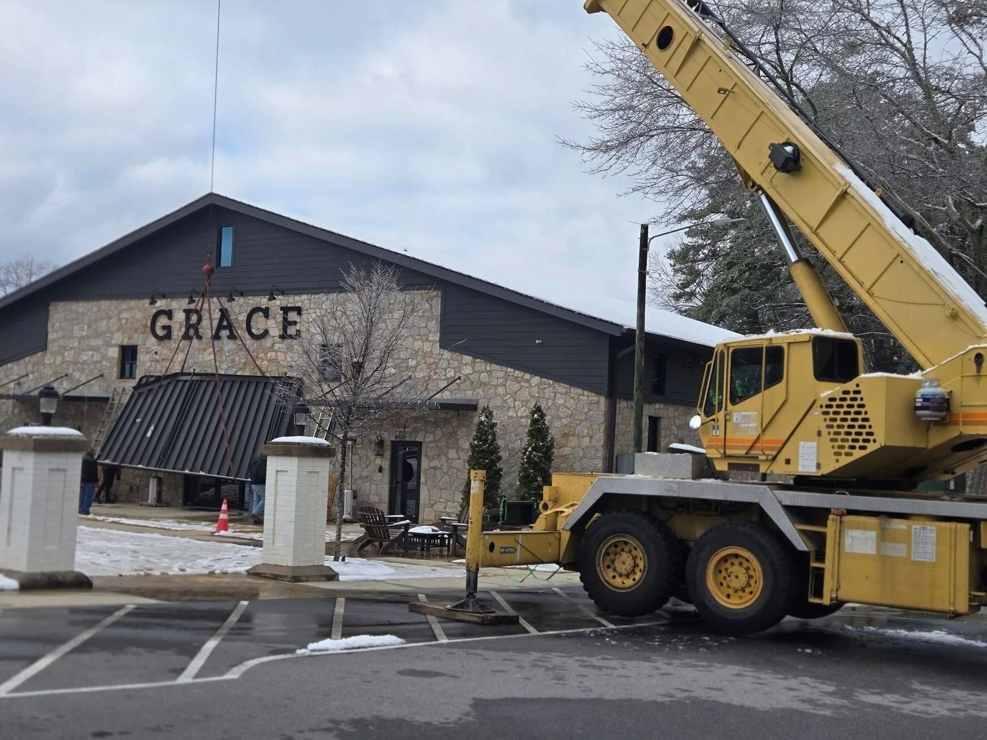 A yellow crane near the Grace building, snow on the ground, overcast sky.