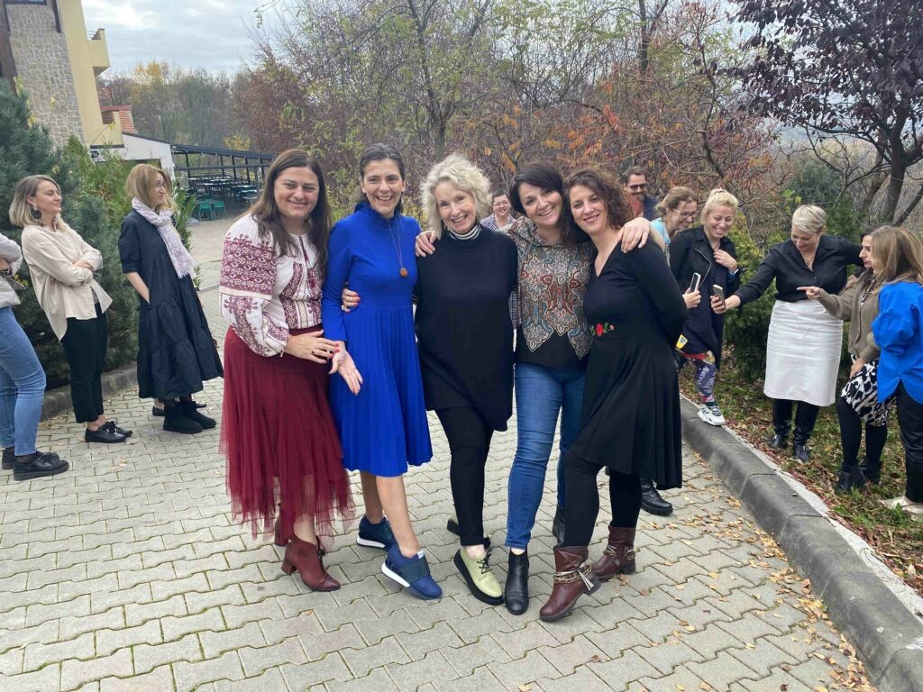 A group of women are posing for a picture on a sidewalk.