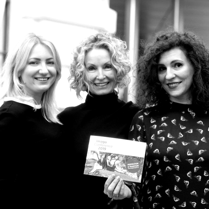Three women are posing for a picture and one is holding a book