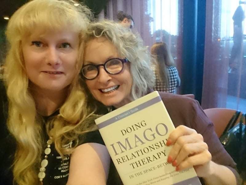 Two women holding a book titled doing imago relationship therapy