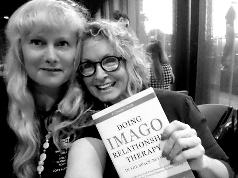 Two women are holding a book titled doing imago relationship therapy