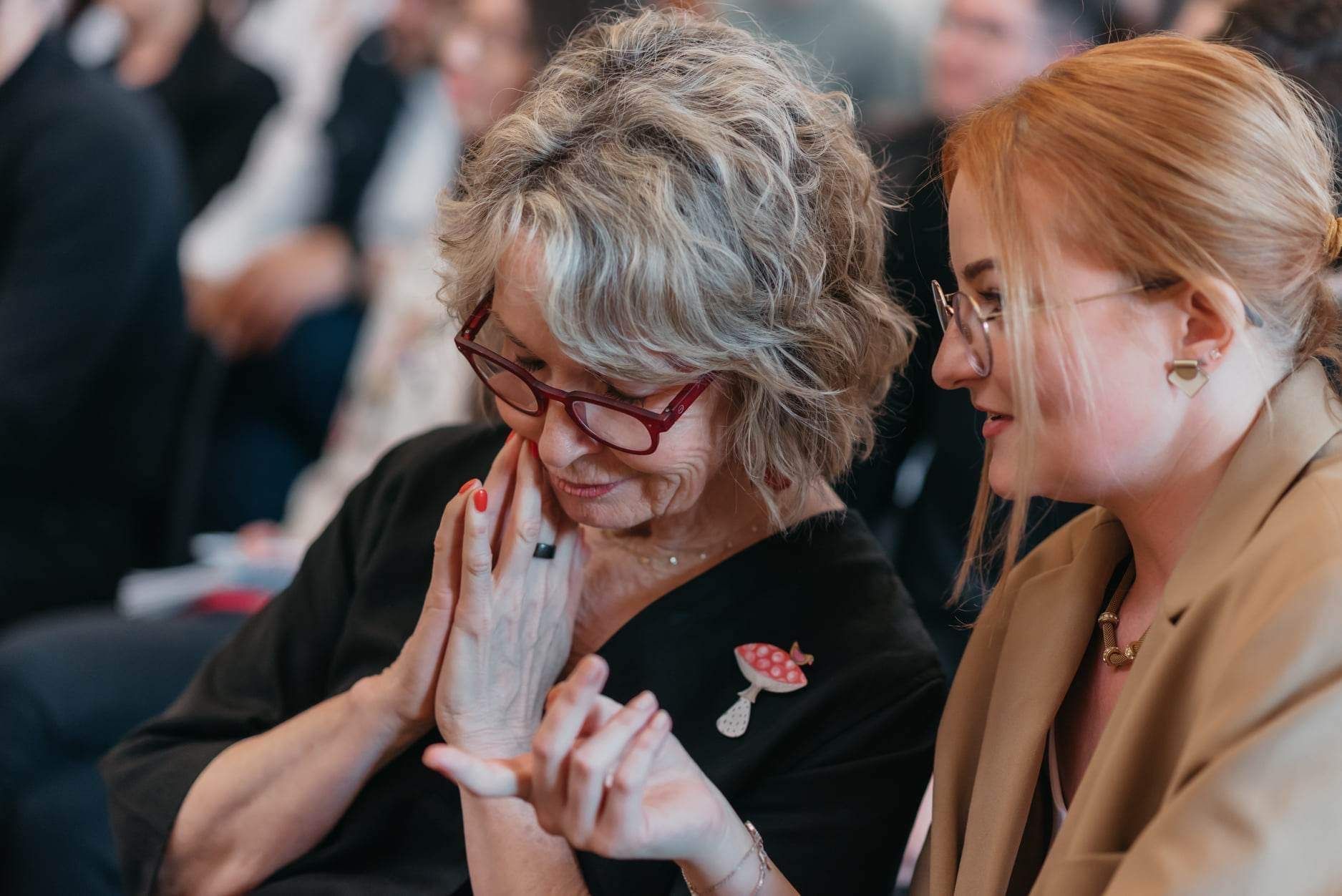 Two women are sitting next to each other in a crowd.