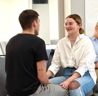 A group of people are sitting in a circle talking to each other.