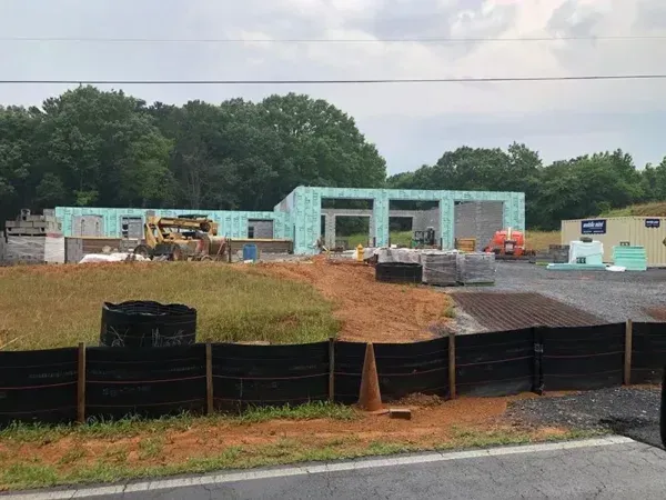 Construction site with a partially built building; green walls, brick piles, and heavy machinery.
