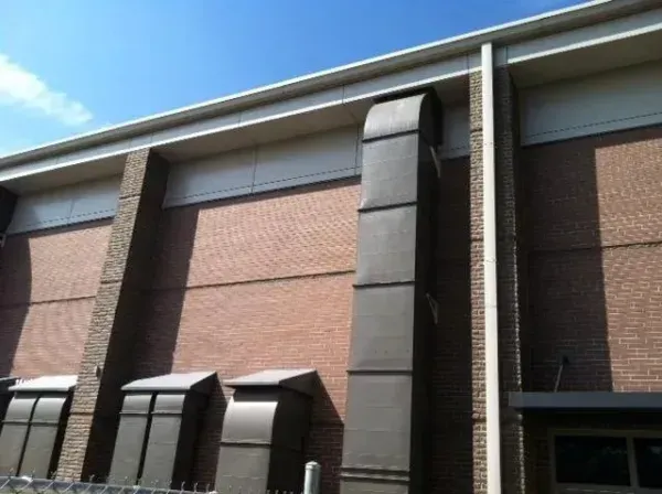 Brick building with ventilation ducts, under a blue sky.