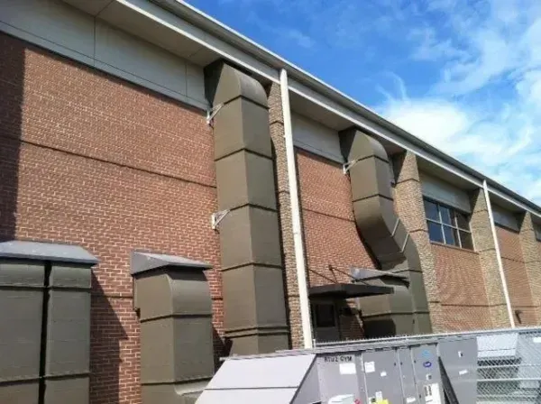 Brick building exterior with large rectangular ventilation ducts extending from the roof.