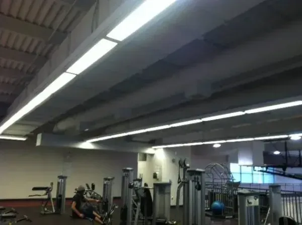 Gym interior with exercise machines under bright ceiling lights.