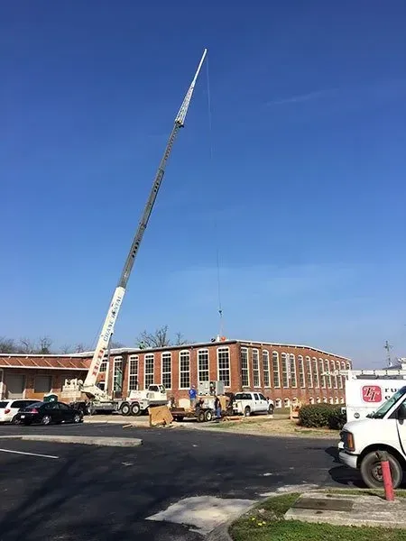 Crane lifting equipment over a brick building. Construction site on a sunny day.