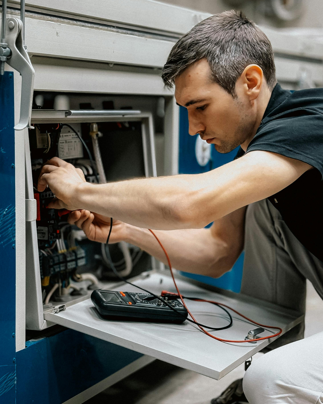 HVAC technician inspecting an outdoor unit. He uses a flashlight, kneeling near his toolbox.