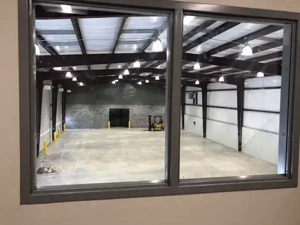 View through a window into a warehouse, concrete floor, metal beams, a forklift.