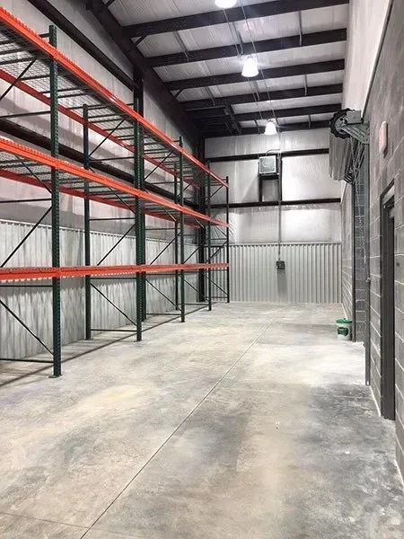 Empty warehouse interior with metal shelving and concrete floor.