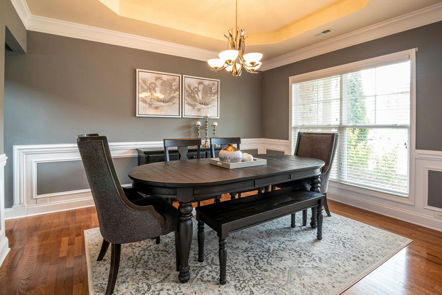 Dining room with dark wooden table, upholstered chairs, and a bench on a patterned rug.