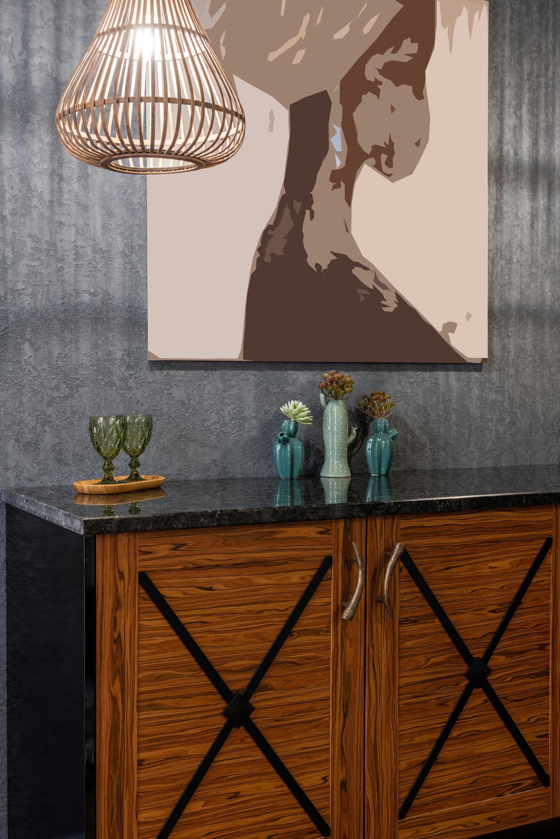Wooden cabinet with black countertop, artwork, hanging light, and decorative vases.