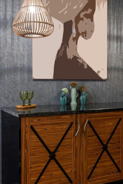 Wooden cabinet with black countertop, artwork, hanging light, and decorative vases.