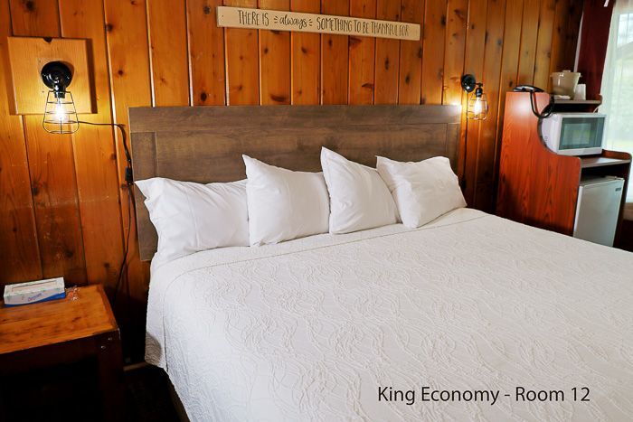 Cozy wood-paneled king bedroom with white bedding, wall lamps, and a small TV