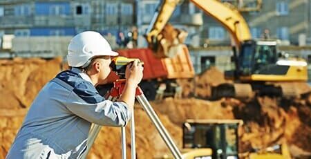 A man is looking through a telescope at a construction site.