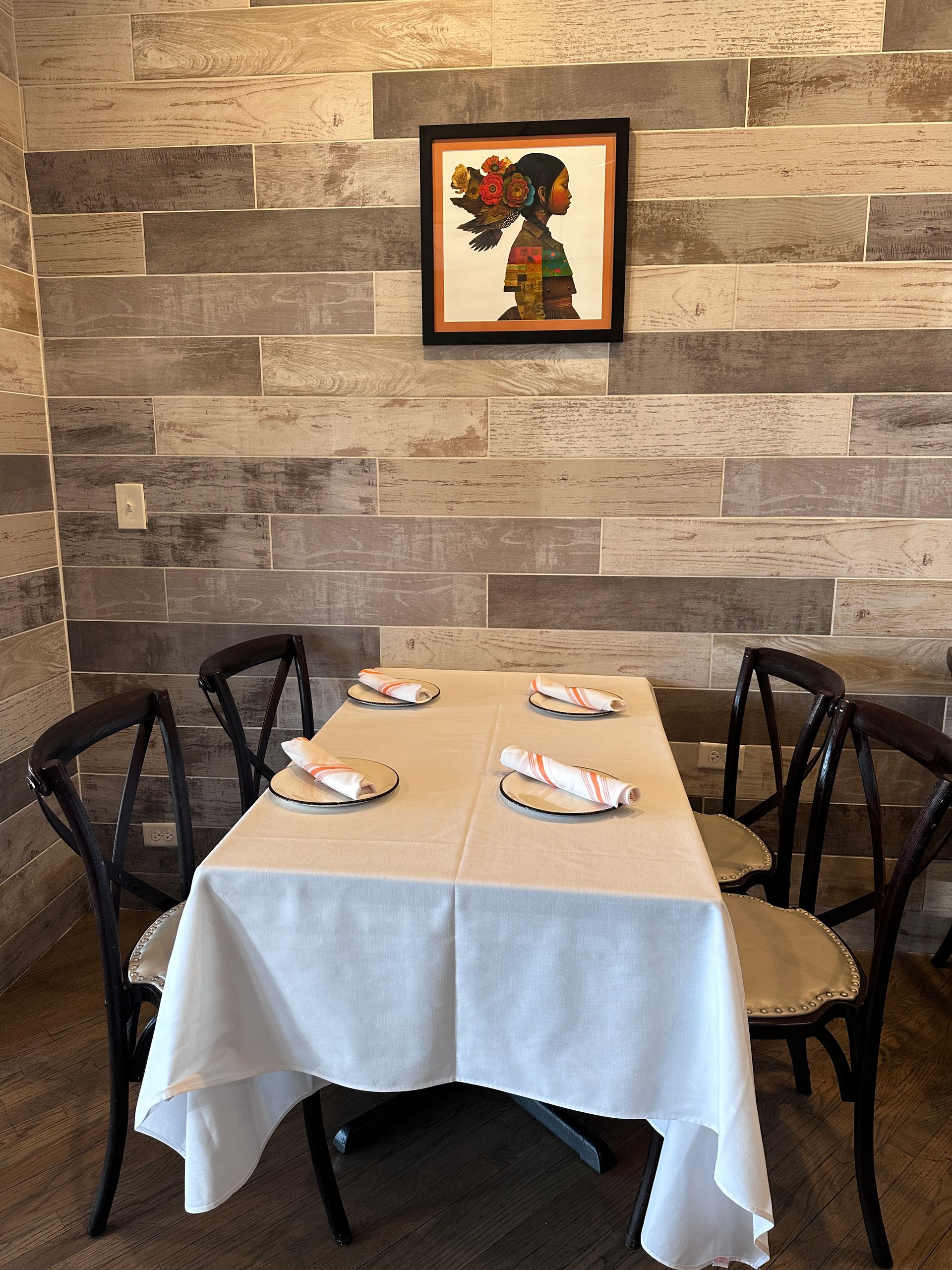 A table and chairs in a room with a picture on the wall above it.