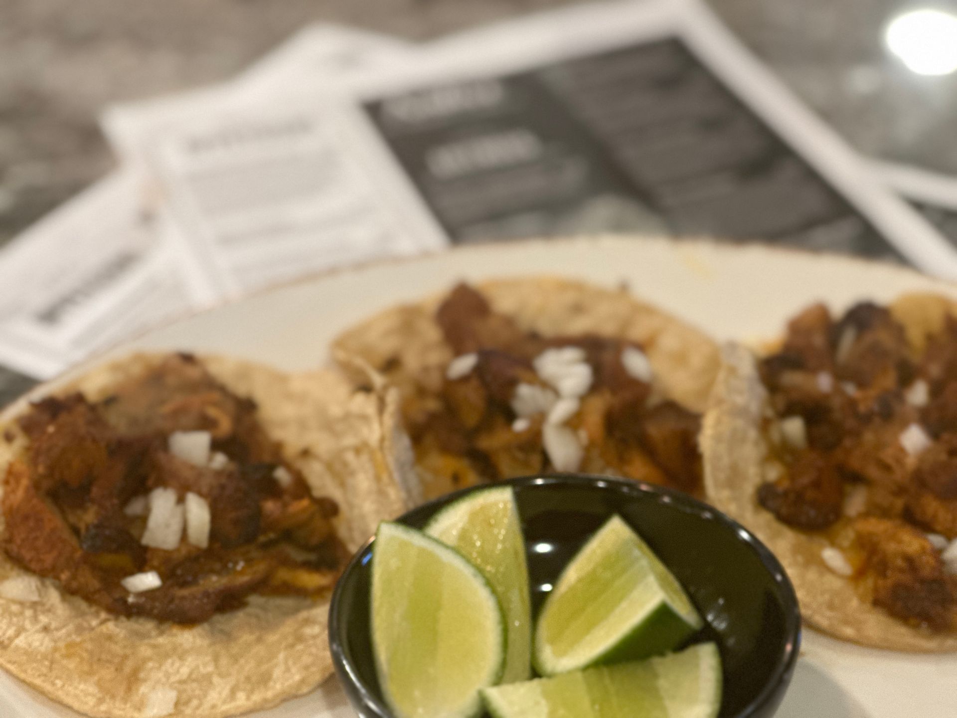 A plate of tacos with a bowl of lime wedges