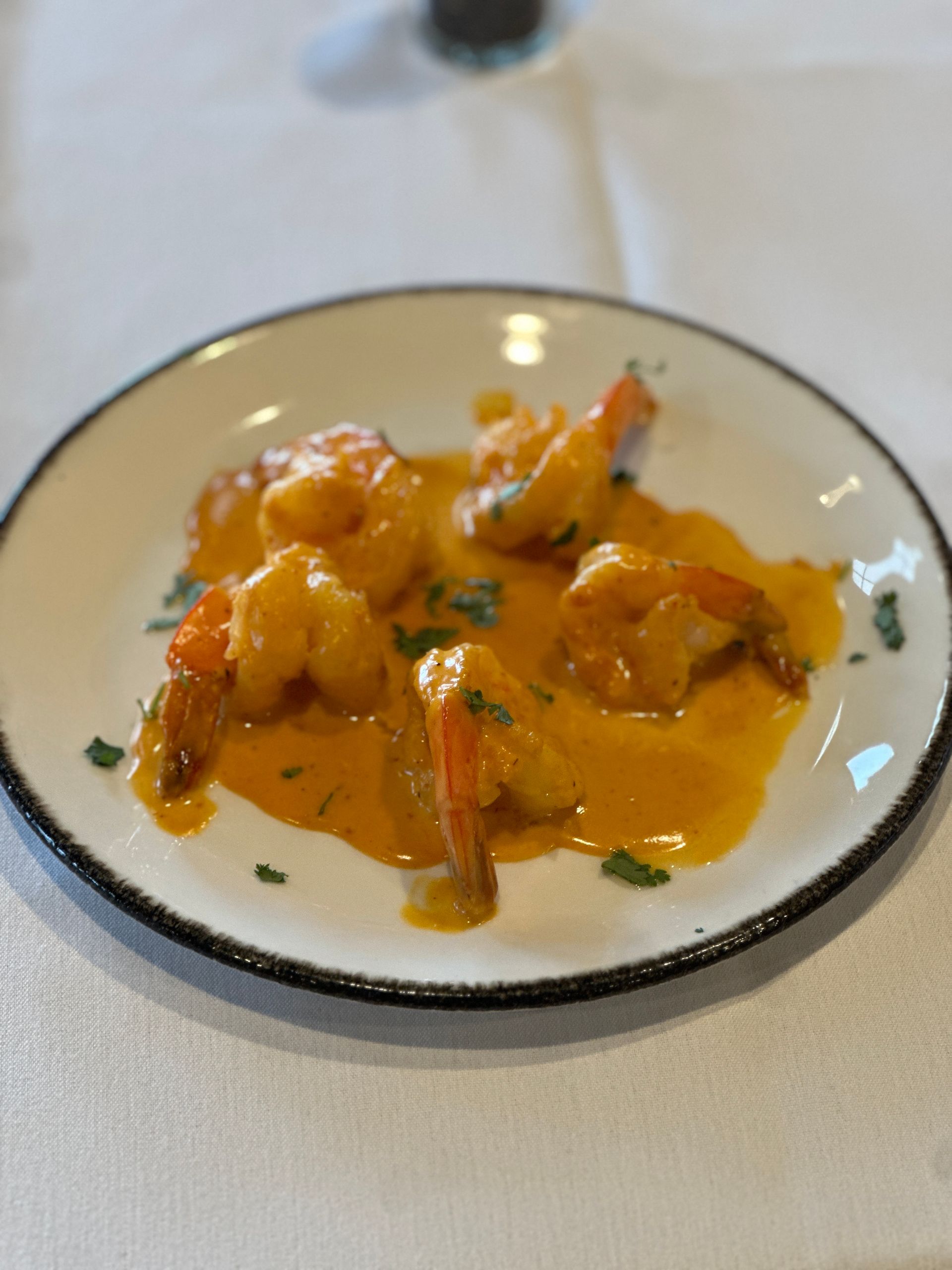 A white plate topped with shrimp and sauce on a table.