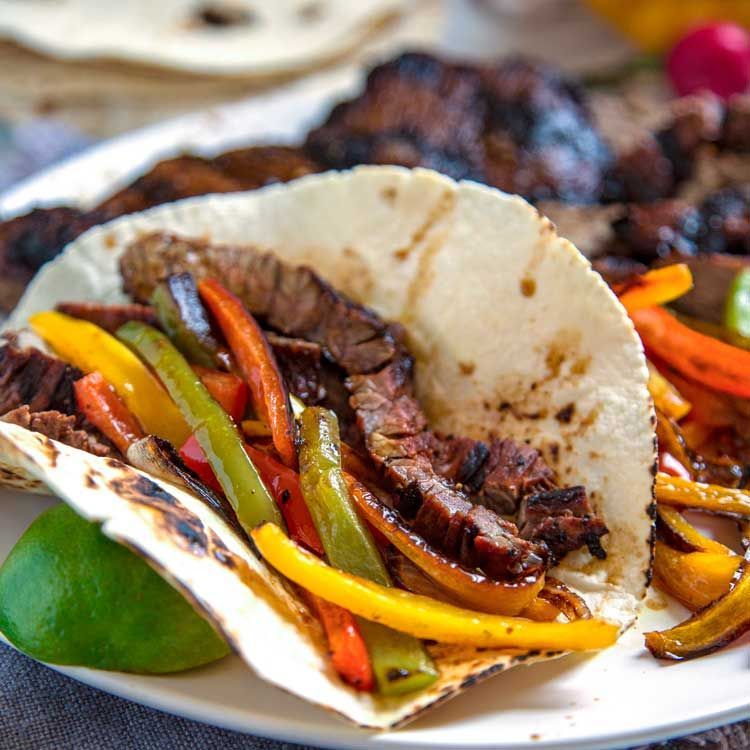 A close up of a taco with meat and vegetables on a plate.