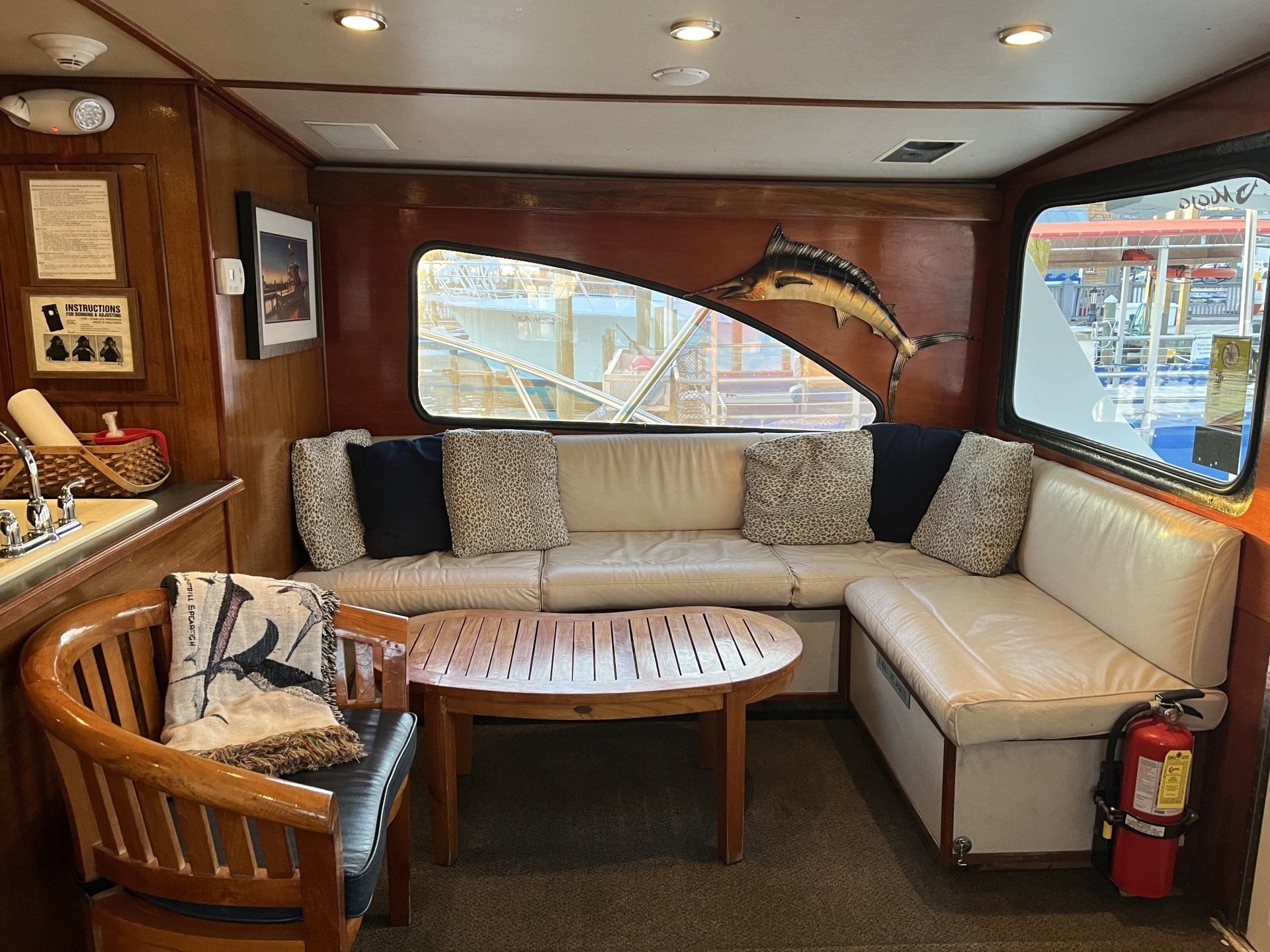 Fishing Destin, FL | Destin Harbor | Charter Boat Relentless | www.charterboatrelentless.com | A Luxury Charter Boat at Everyday Rates | 65' x 20' | A living room with a couch , chair , table and a fire extinguisher.