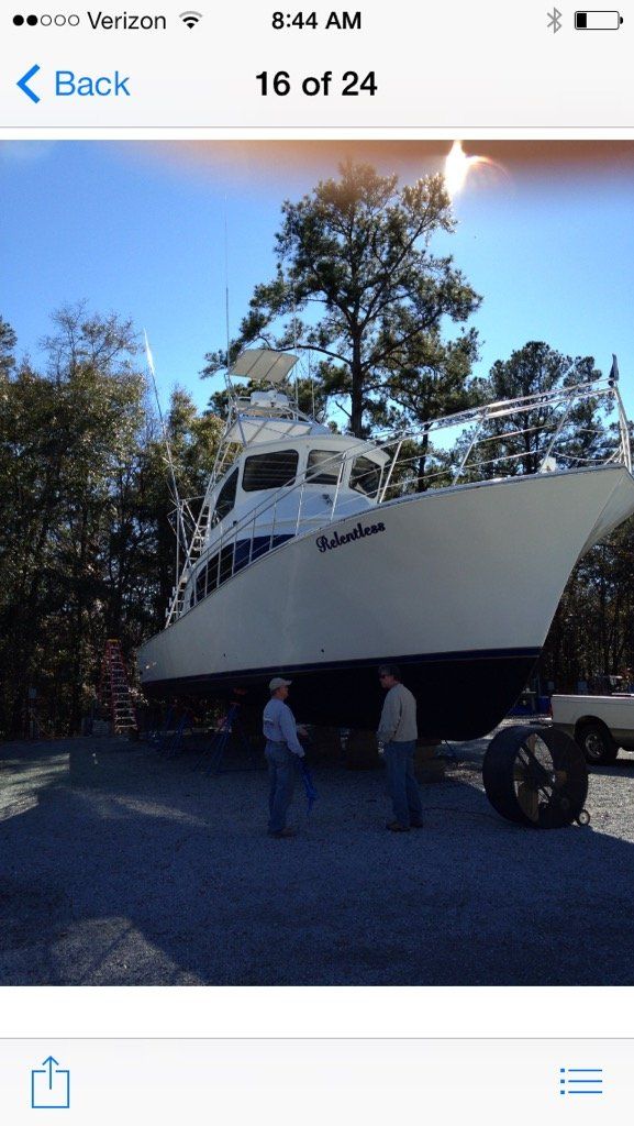 A phone screen shows a picture of a boat in a parking lot