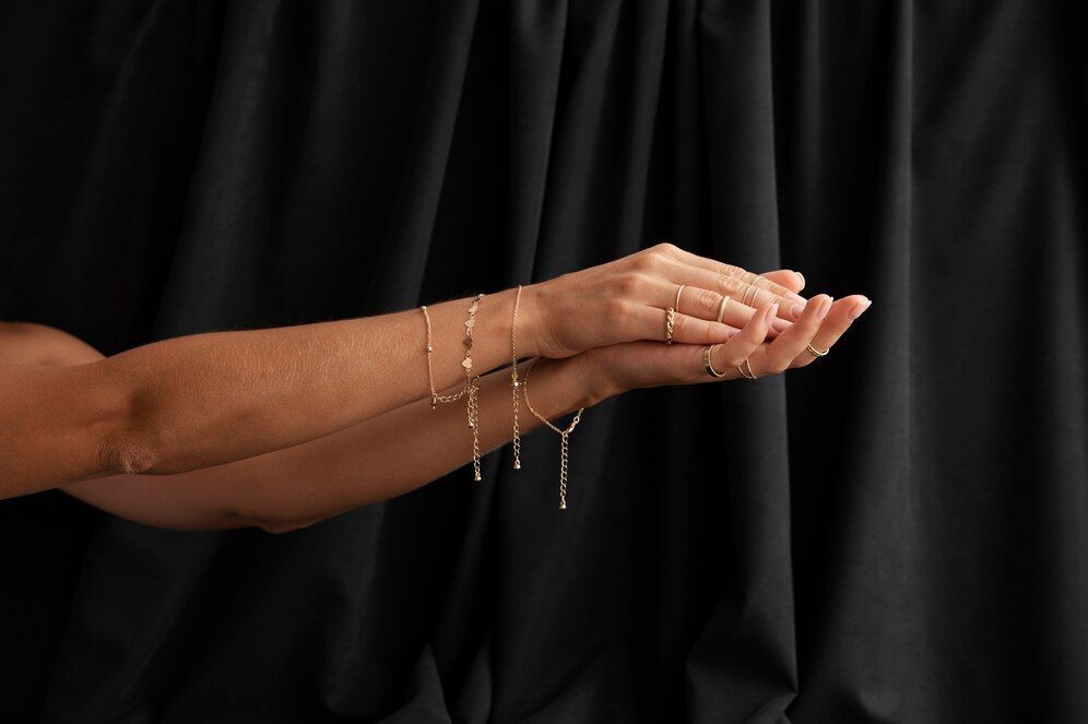 A woman is holding her hands together in front of a black curtain.