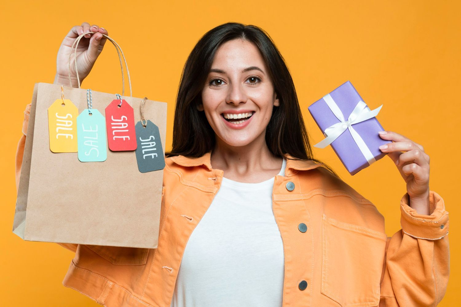 A woman is holding shopping bags and a gift box.