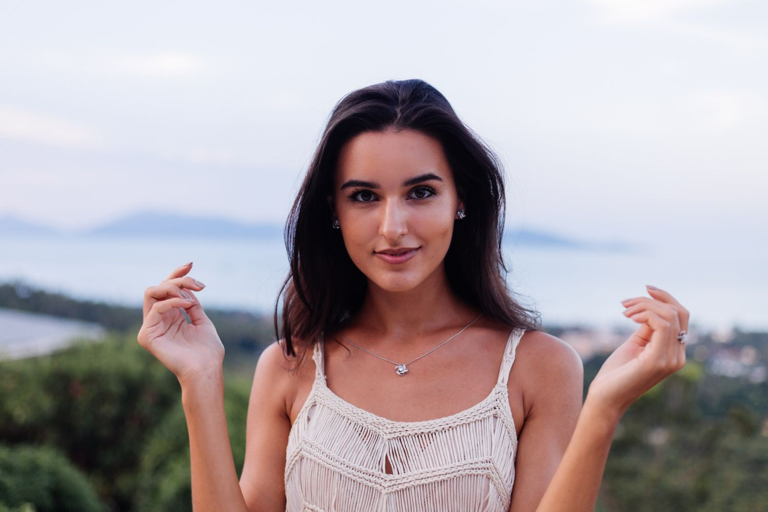 The woman is wearing a white tank top and a necklace.