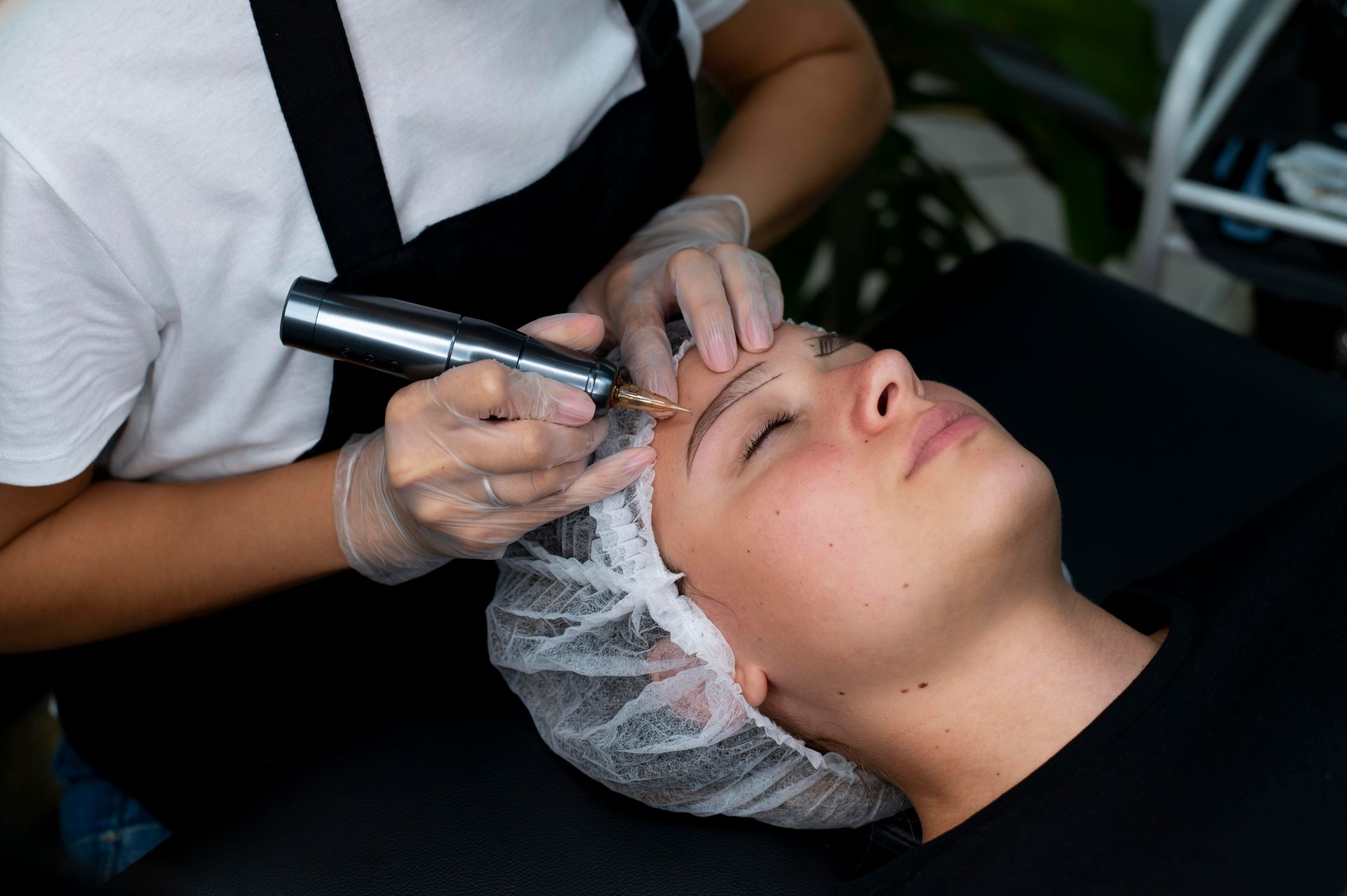 A woman is getting a tattoo on her eyebrows.