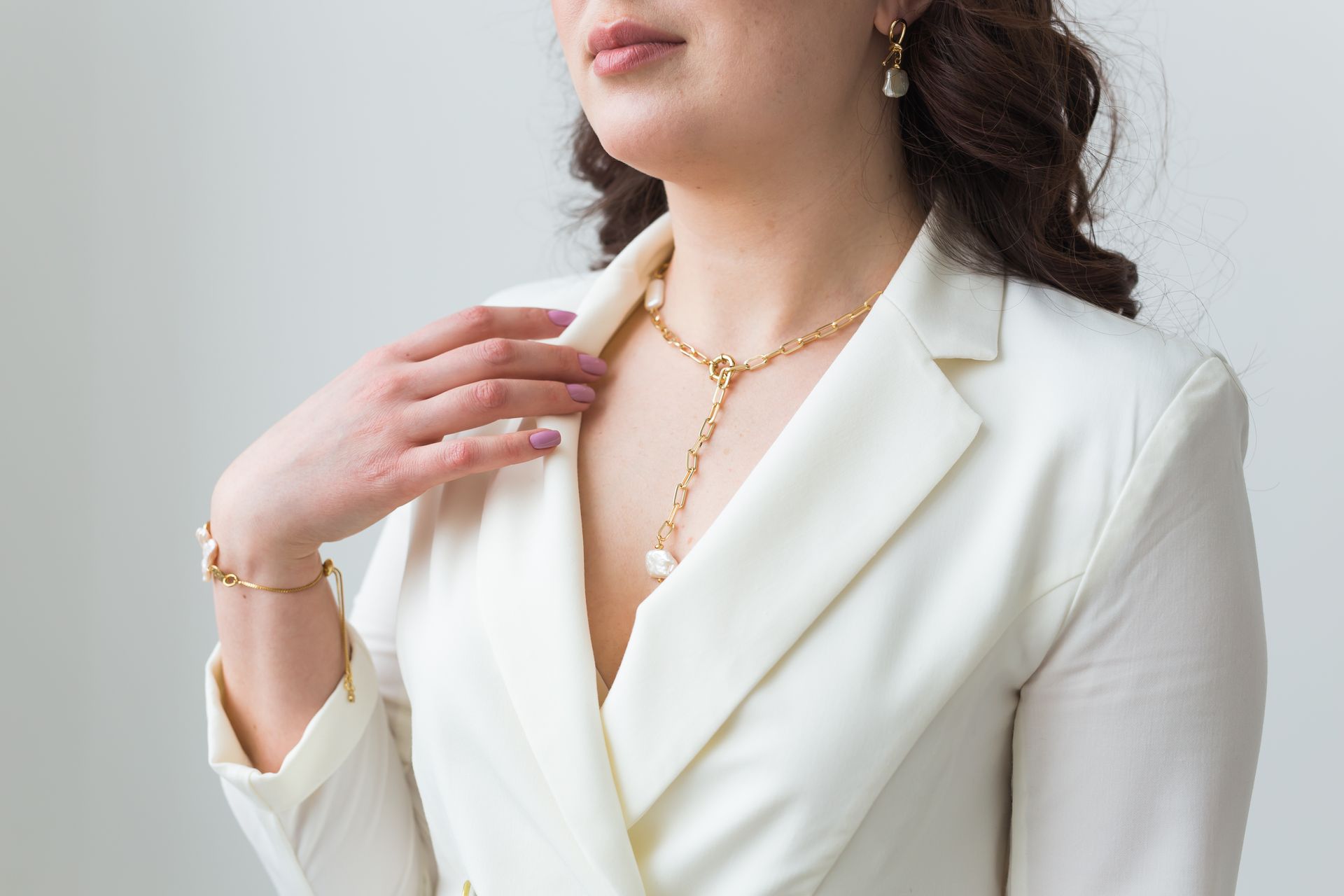 Woman in white blazer with gold jewelry