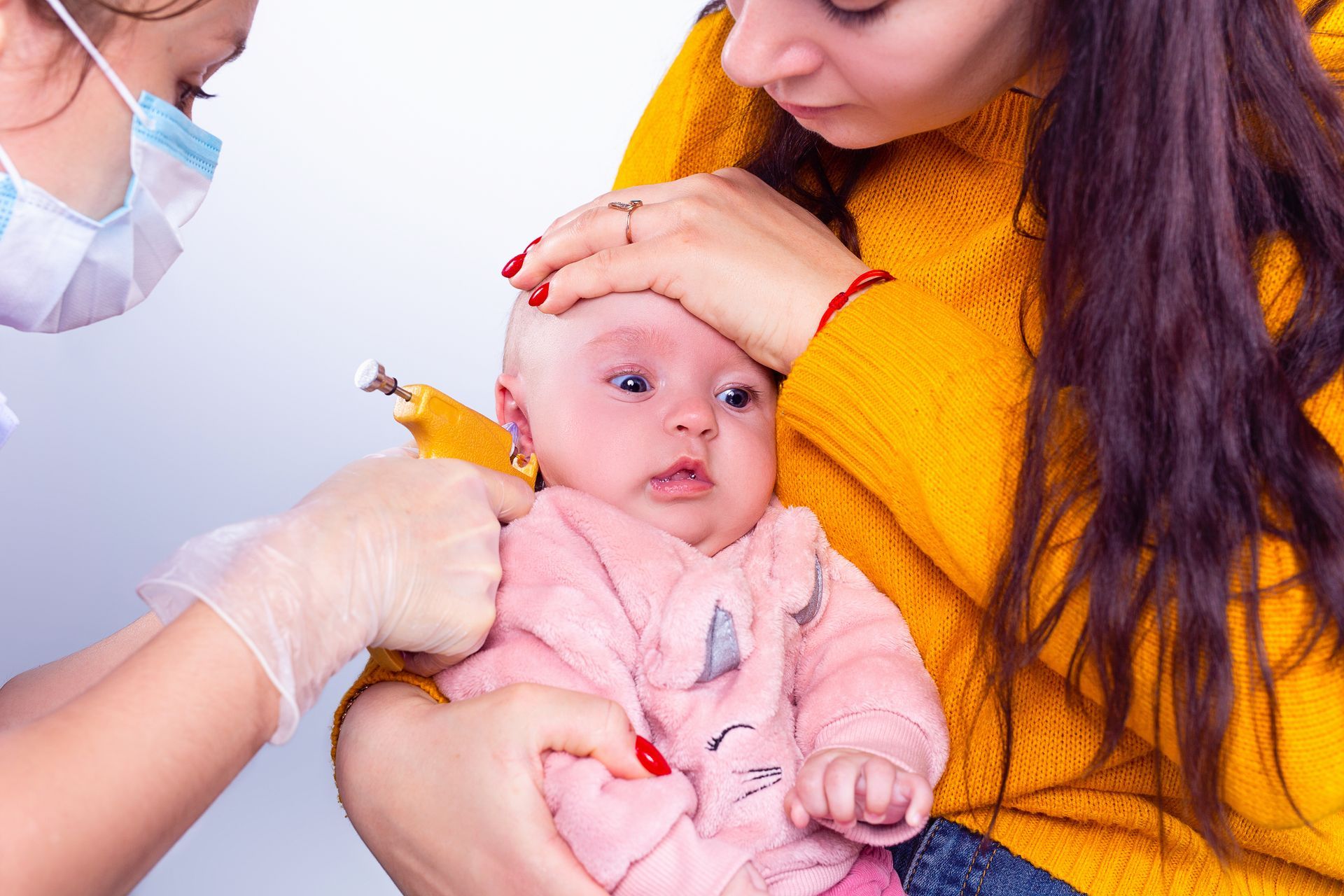 A baby is getting her ears pierced by a doctor.