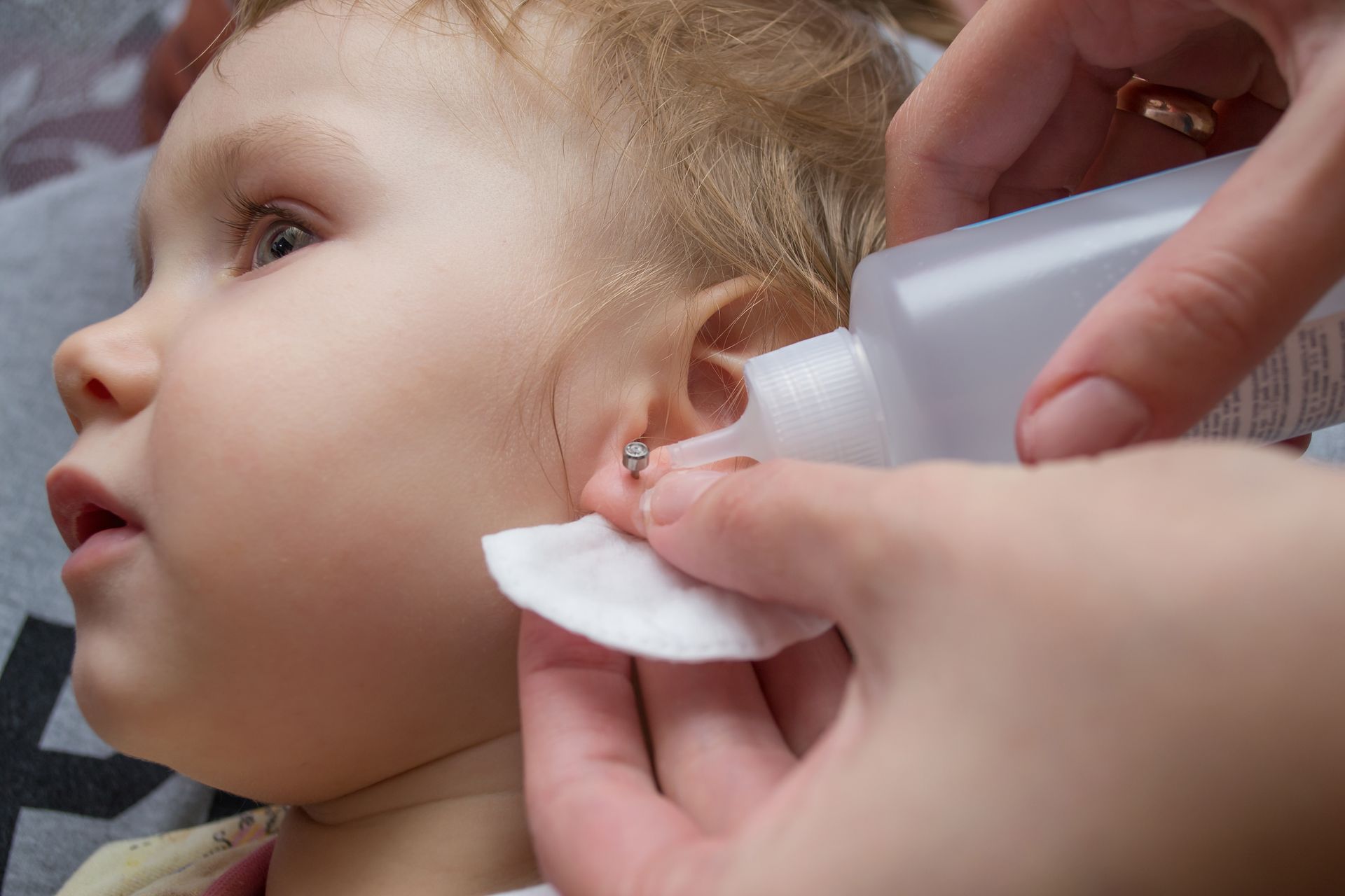 A woman is cleaning a baby 's ear with a cotton swab.