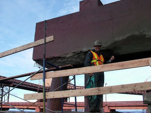 Un homme portant un casque et un gilet de sécurité se tient debout sur un pont.