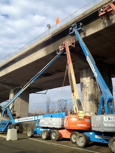 Une rangée de véhicules de construction est garée sous un pont