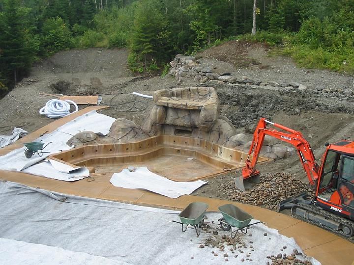 Une pelleteuse travaille sur une piscine au milieu d une forêt.