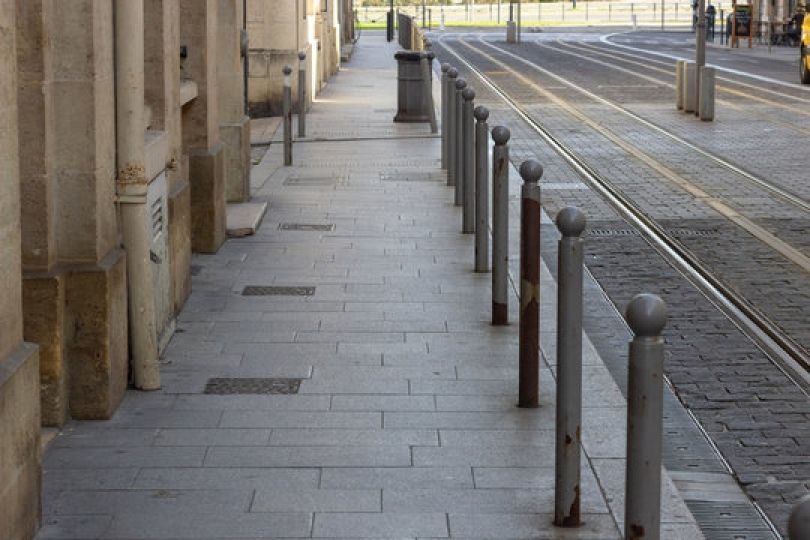 Une rangée de poteaux sur un trottoir à côté d une voie ferrée