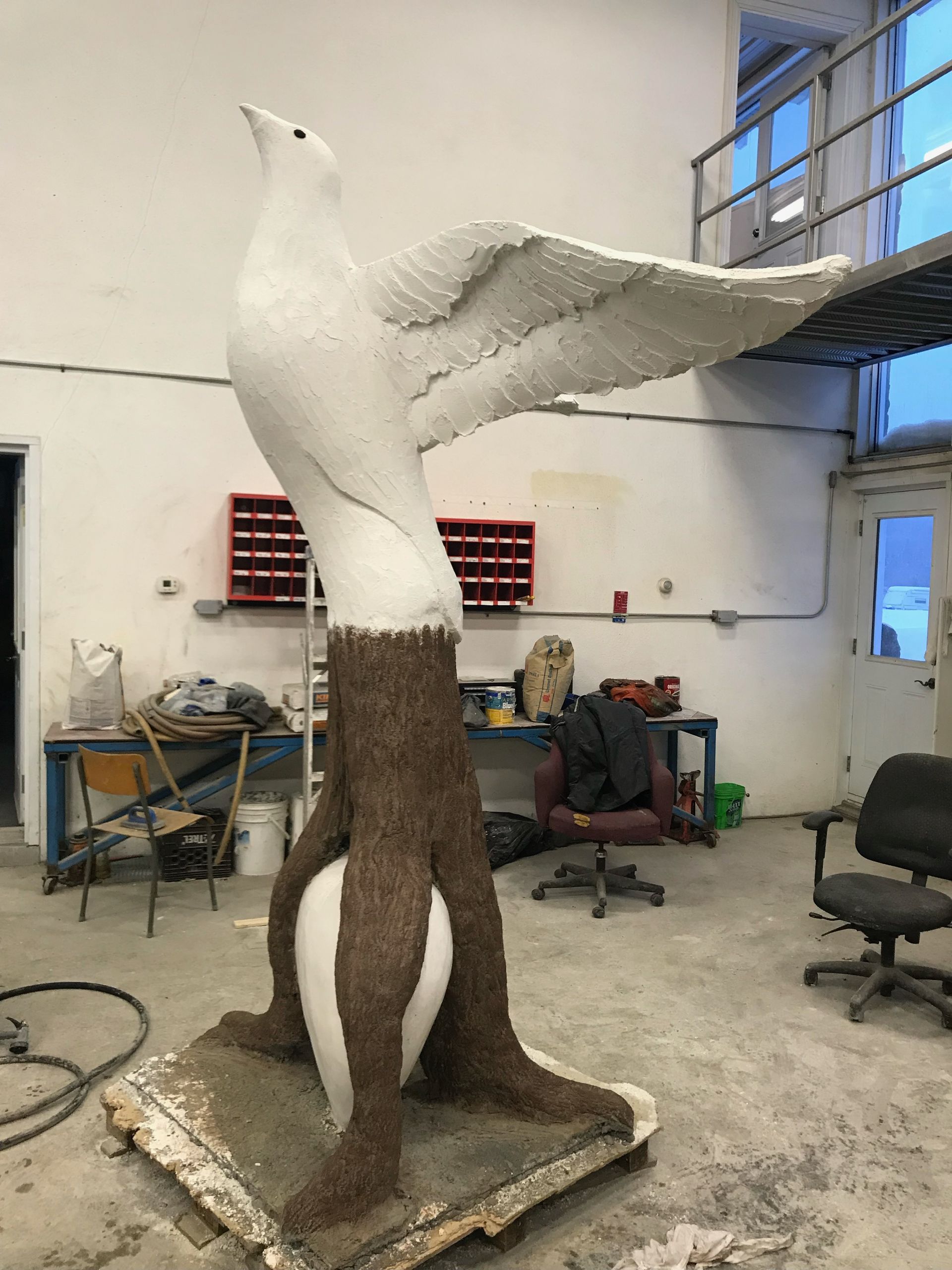 Une statue d un oiseau assis sur une souche d arbre dans une pièce.