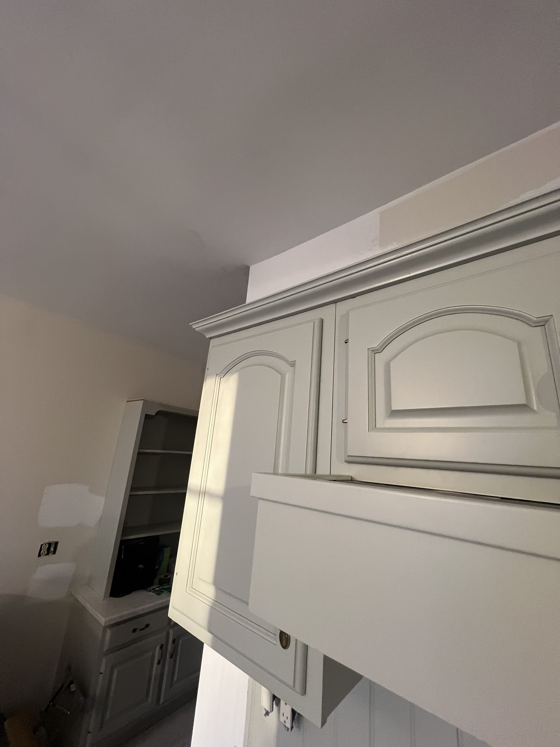 Kitchen cabinets and shelves, light gray, with white ceiling and walls.