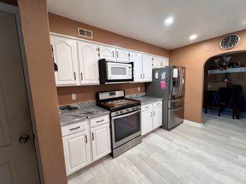 Kitchen with stainless steel appliances, light brown cabinets, and white countertop.