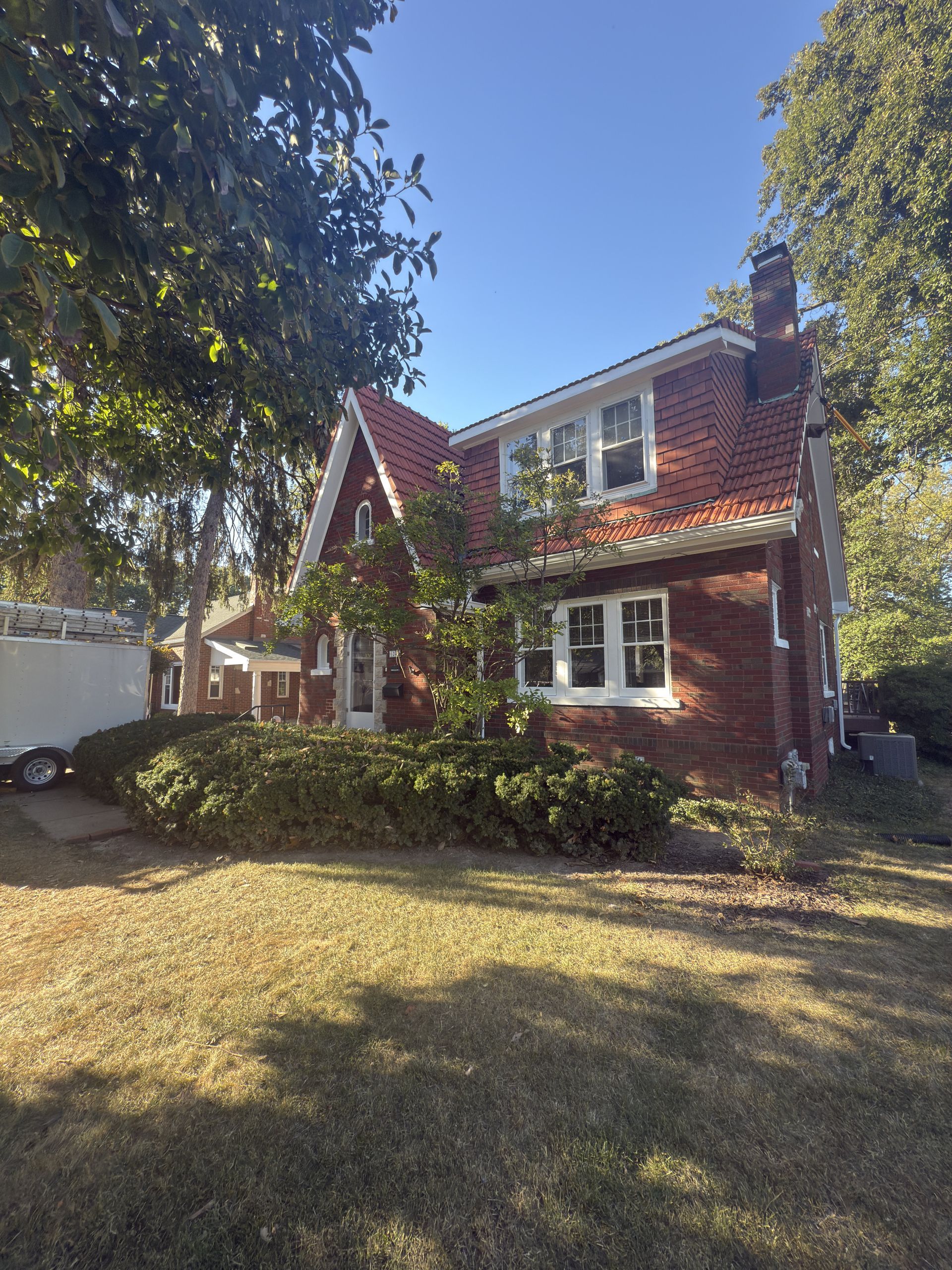 Hand holding a paint roller applying white paint to a light blue wall.