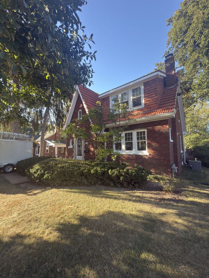 Hand holding a paint roller applying white paint to a light blue wall.