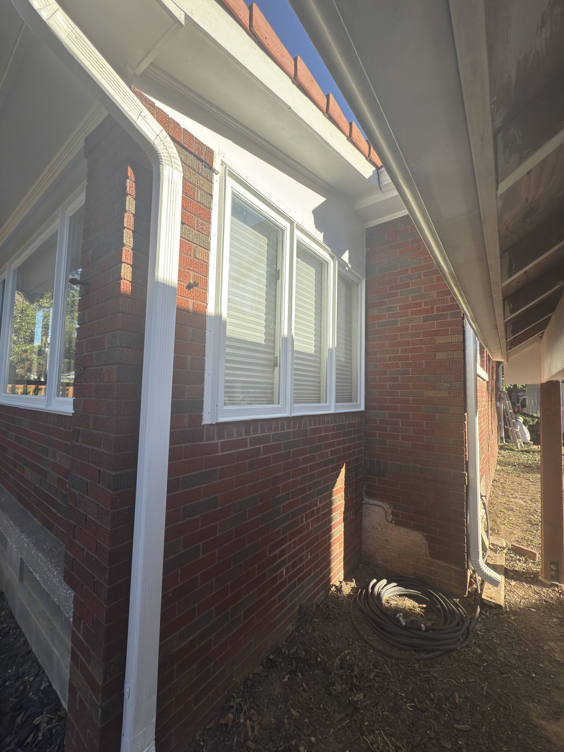 Red brick building with white trim around windows and eaves; gutters visible.