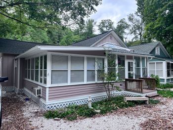 A person uses a textured paint roller on a light tan exterior wall.