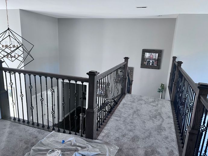 Two open paint cans with orange paint and paintbrushes.