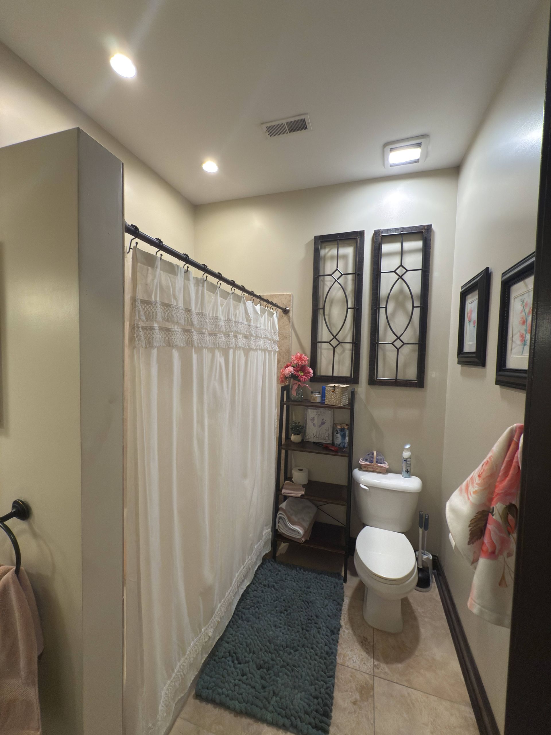 Bathroom with white shower curtain, beige walls, and a toilet.