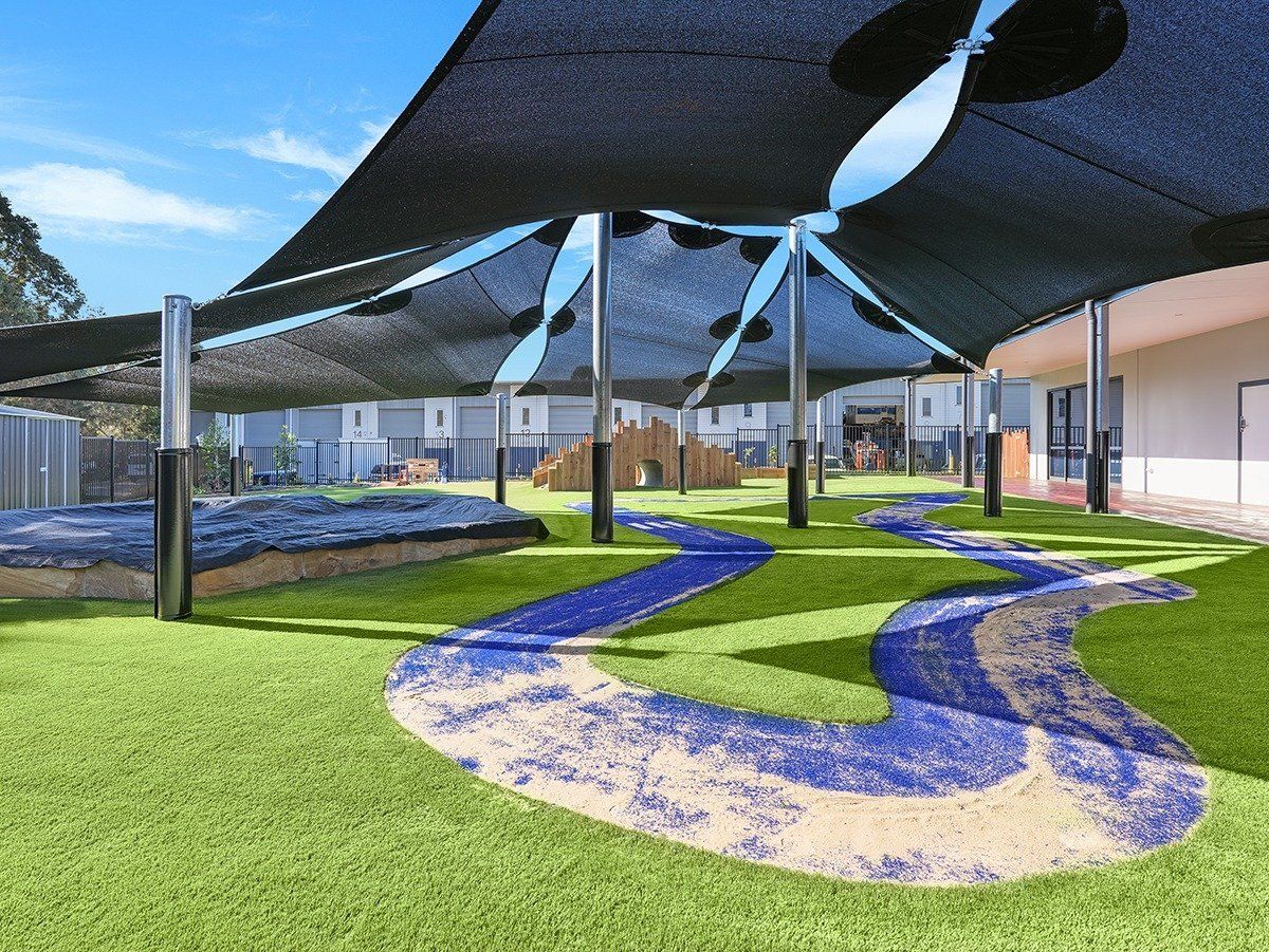 An artist 's impression of a playground with shades and a path.