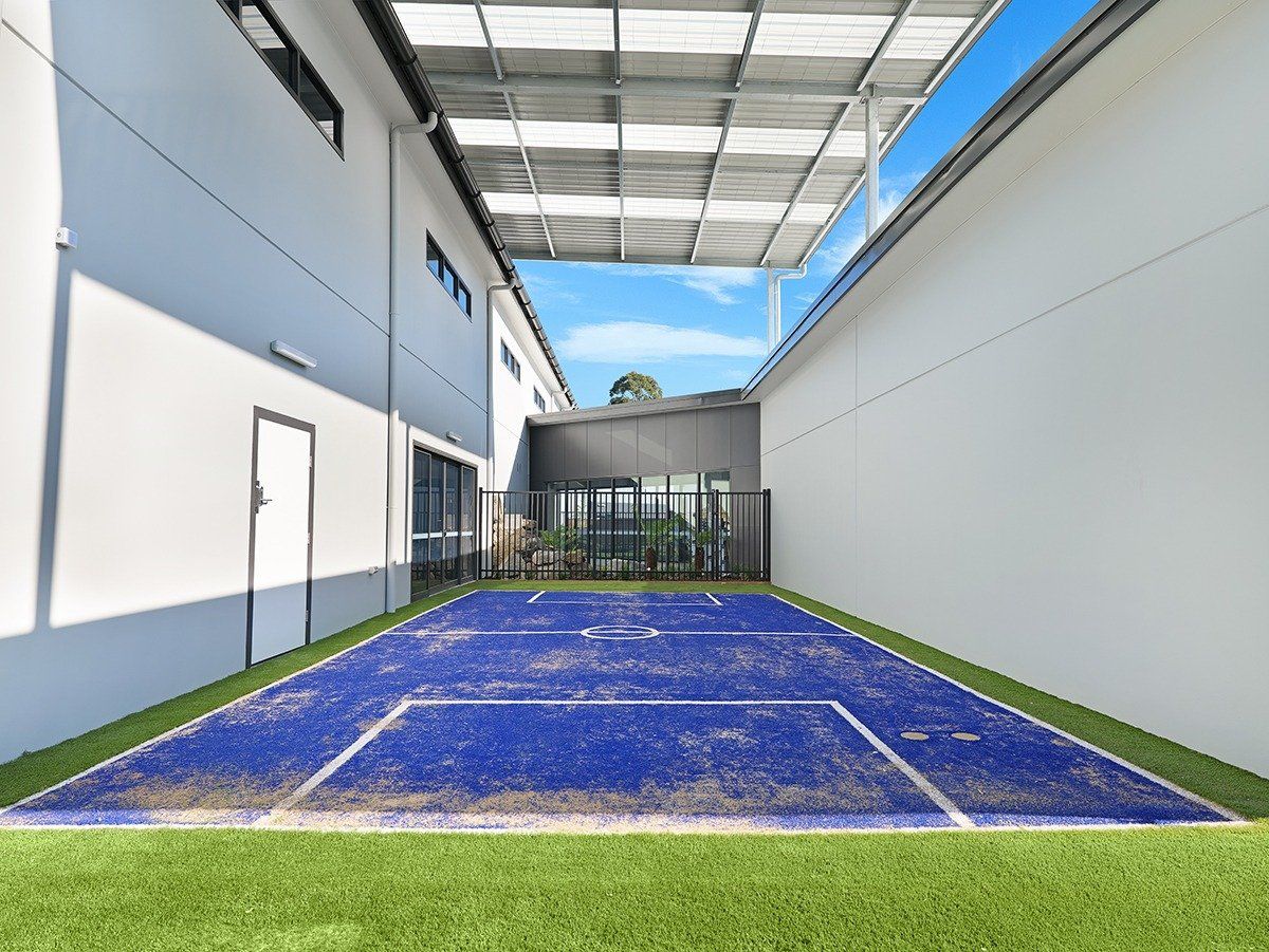 There is a basketball court in the backyard of a building.